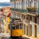 Colorful traditional Portuguese tiles and architecture in Lisbon narrow street with yellow tram passing through